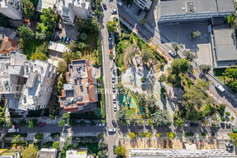 Ανέβαστο φωτογραφία γειτονιάς με κήπο, δρόμο και πράσινο περιβάλλον.