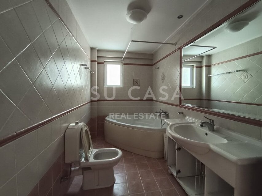 Ανθρώπινη μπανιέρα και τουαλέτα σε μοντέρνο μπάνιο με φυσικό φωτισμό.
