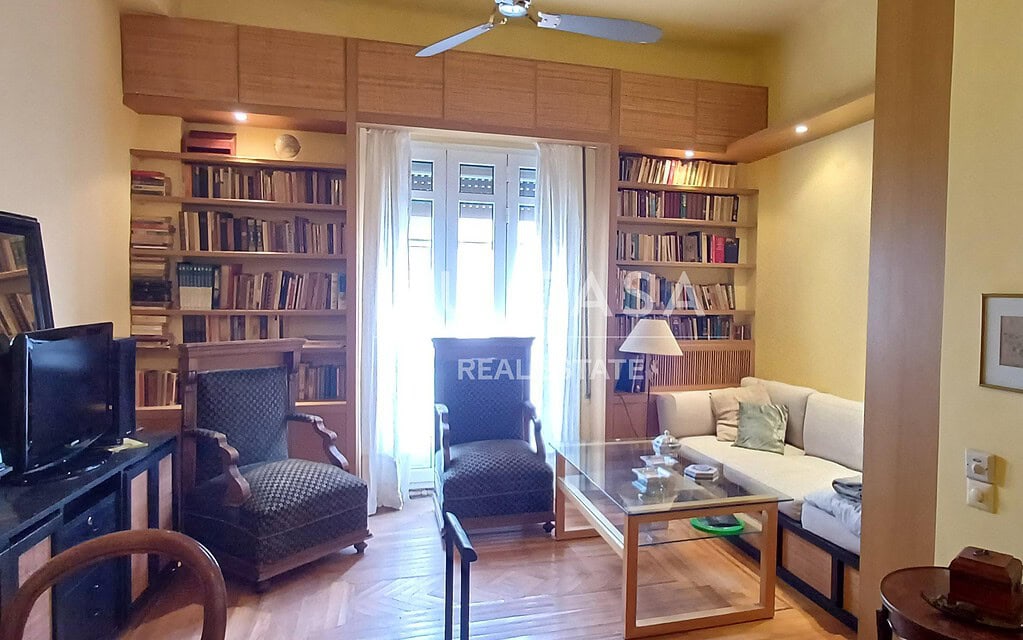 Ανθρώπινο σαλόνι με βιβλιοθήκες, καναπέ και πολυθρόνες, φωτεινό και άνετο, ιδανικό για χαλάρωση και.