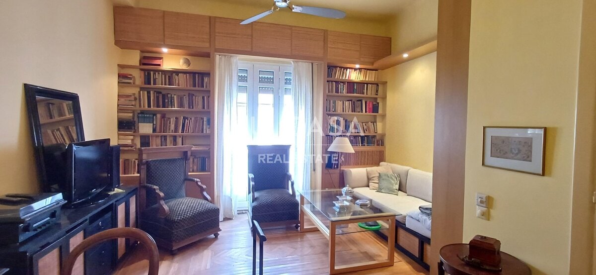 Ανθρώπινο σαλόνι με βιβλιοθήκες, καναπέ και πολυθρόνες, φωτεινό και άνετο, ιδανικό για χαλάρωση και.