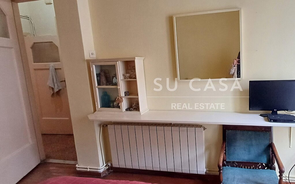 Εσωτερικό δωμάτιο με καθρέφτη, τηλεόραση και καρέκλα, φωτεινό και άνετο.
