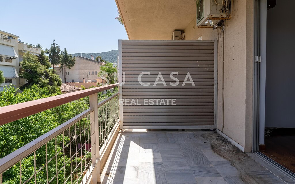 Εξωτερική βεράντα διαμερίσματος με θέα σε πράσινο τοπίο, ιδανική για χαλάρωση και απολαυστικές στιγμ.