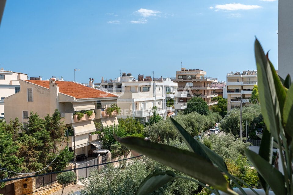 Θέα από διαμέρισμα στην Αθήνα με πράσινα δέντρα και πολυκατοικίες.