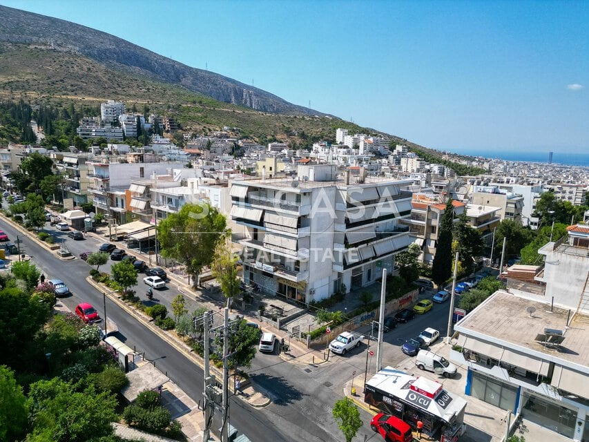 Οικία σε αστικό περιβάλλον με βουνό και θάλασσα στο βάθος.