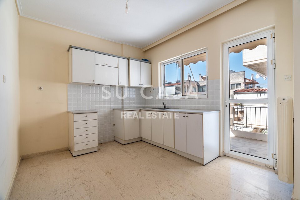 Εσωτερική κουζίνα με λευκά ντουλάπια και παράθυρα σε διαμέρισμα Su Casa.