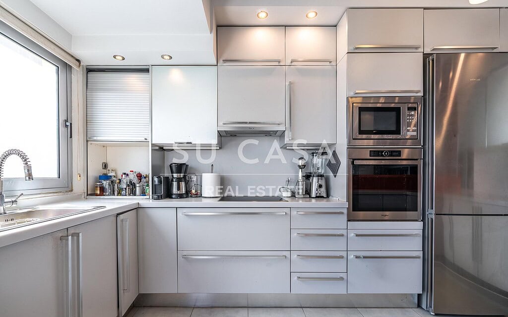 Μοντέρνα κουζίνα Su Casa με λευκά ντουλάπια και inox συσκευές.