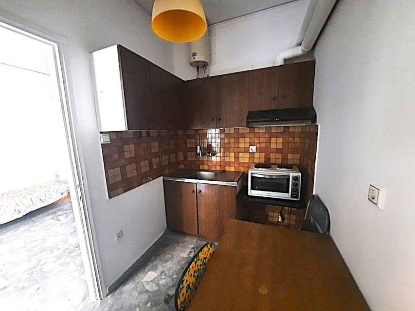Μικρή κουζίνα με ξύλινα ντουλάπια και ηλεκτρική συσκευή.
