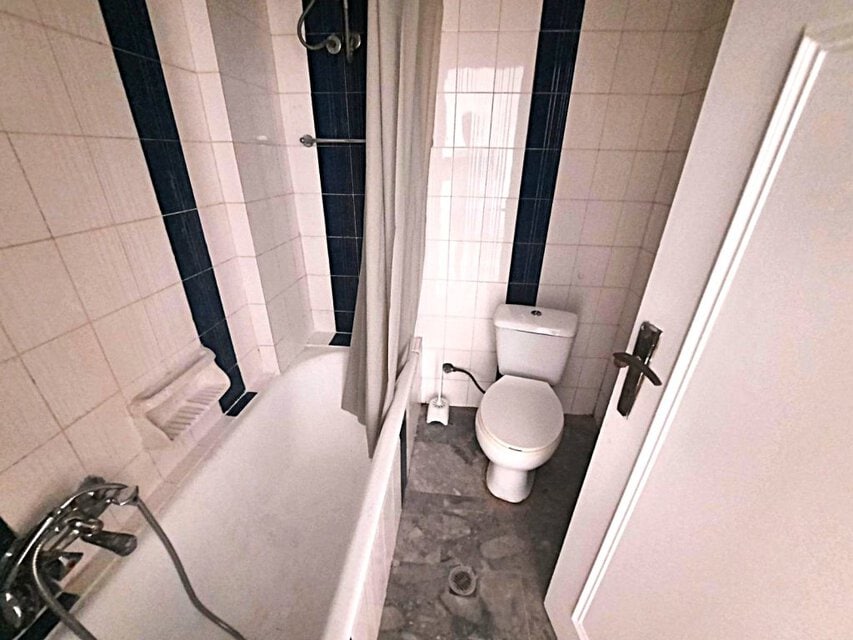 Μπάνιο σε γκαρσονιέρα με ντους και τουαλέτα, μικρό και λειτουργικό.