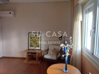 Εσωτερικό σαλόνι με παράθυρο, διακόσμηση και ξύλινο πάτωμα.